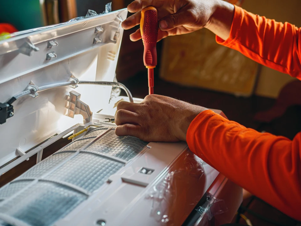 Main d'un technicien utilise un tournevis pour serrer les écrous de l'ensemble de climatisation, des techniciens de l'air conditionné Préparez-vous à installer un nouveau climatiseur dans les maisons