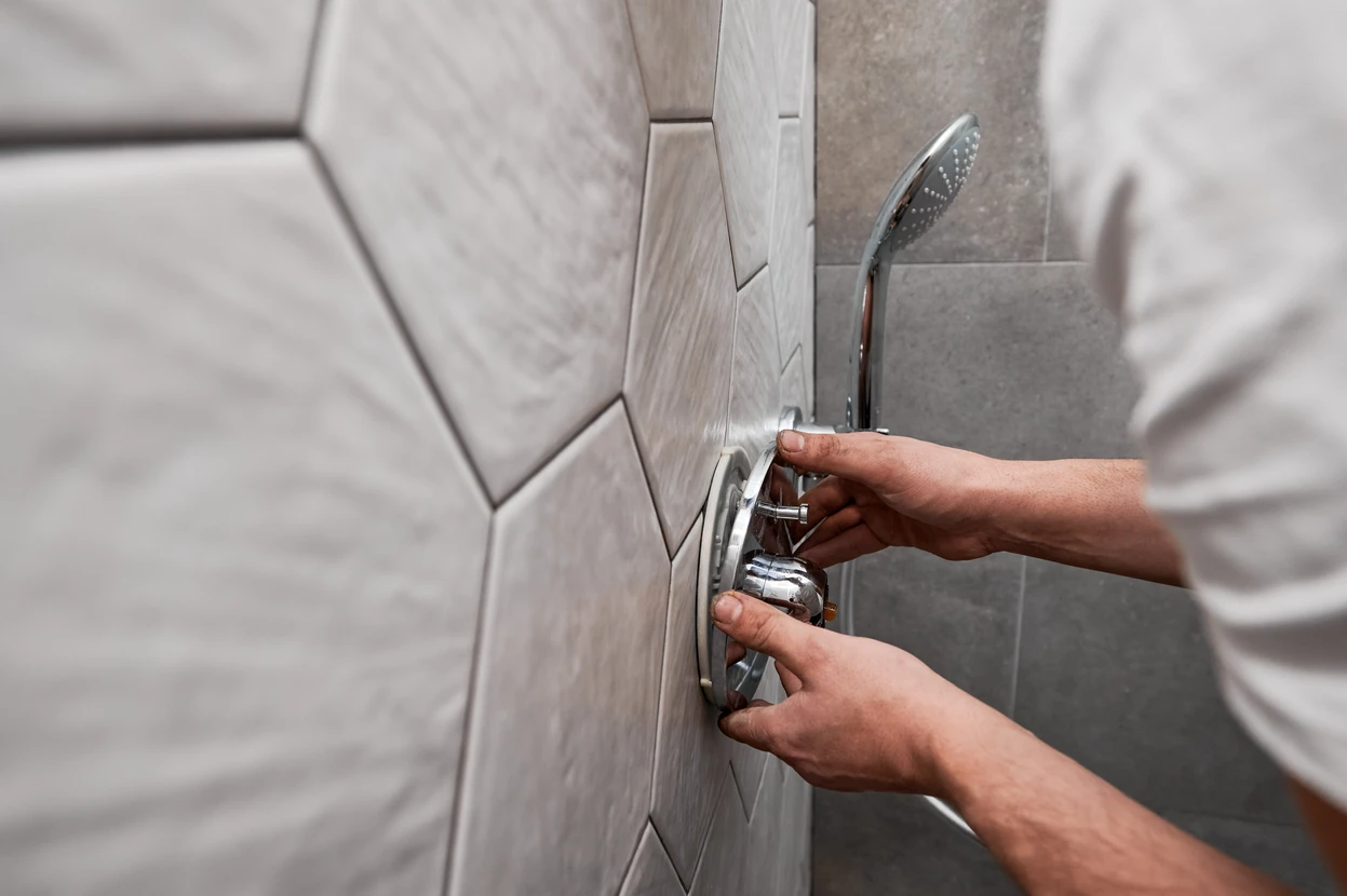 Homme effectuant la maintenance d'une robinetterie de douche dans une salle de bains moderne