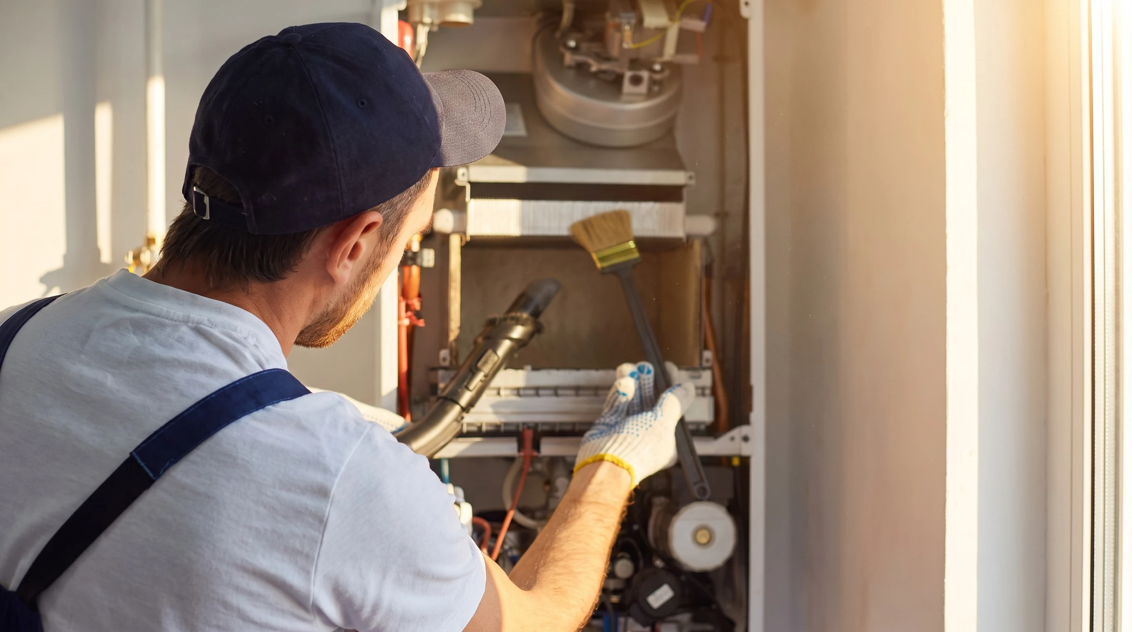 Un technicien en uniforme effectue la maintenance d'une chaudière à gaz domestique